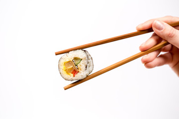 Hand holding Sushi roll with bamboo chopsticks isolated on white