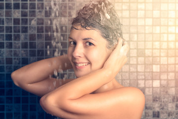 Naklejka premium Frau massiert Shampoo in ihre Haare unter der Dusche