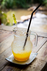 Iced passion fruit soda in jar on a wooden table on waterfall ba