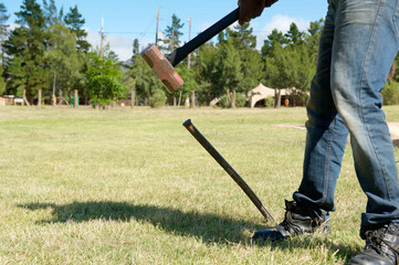 Man with sledgehammer hitting large metal spike
