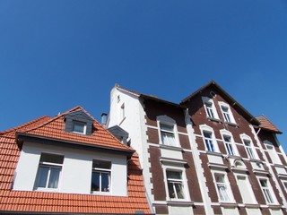 Restaurierte Altbauten mit Spitzgiebel, Mansarden und Dachgaube vor blauem Himmel im Sonnenschein...