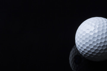 Golf ball isolated on dark background with space for text.