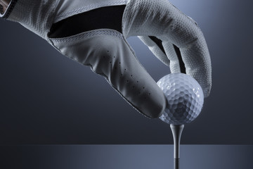 Close up of hand putting a golf ball on tee.