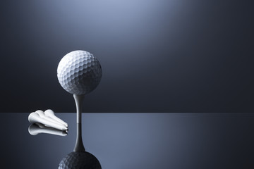 Golf ball on tee isolated on dark blue reflective background.