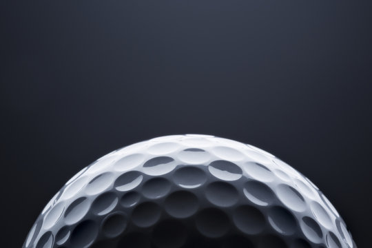 Macro golf ball on dark blue  background, space for text.