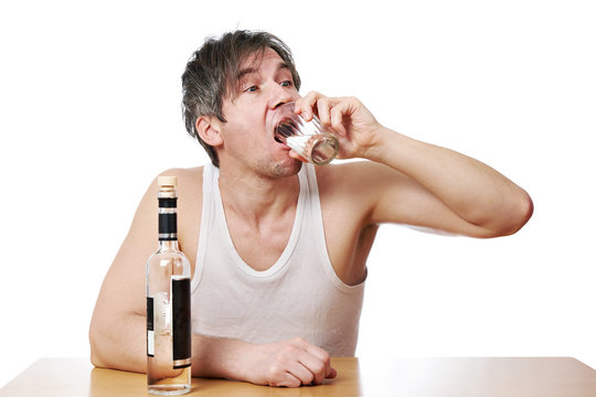 Drunk man drinks a glass of vodka