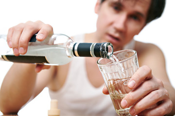 Drunk man pours vodka into a glass closeup