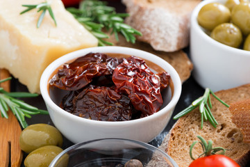 sun-dried tomatoes in a bowl and various appetizers, close-up
