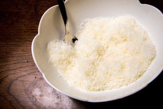 Formaggio grattugiato nella ciotola di ceramica bianca