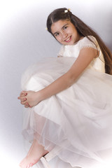 Smiling girl with communion dress possing sitting on a chair and