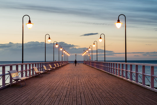 Drewniane molo o brzasku z zapalonymi latarniami