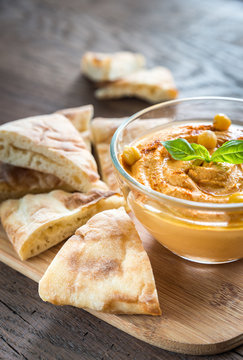 A bowl of hummus with pita slices