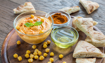 A bowl of hummus with pita slices
