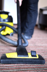 Maid cleaning the carpet with vacuum cleaner