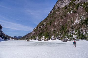 man trekking across a frozen lake