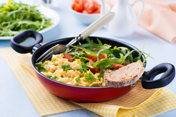 Scrambled eggs with fresh salad in frying pan