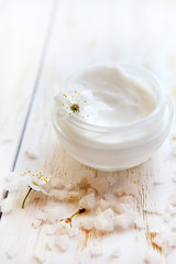 Fototapeta na wymiar Pot of beauty cream surrounded by flowers and sea salt