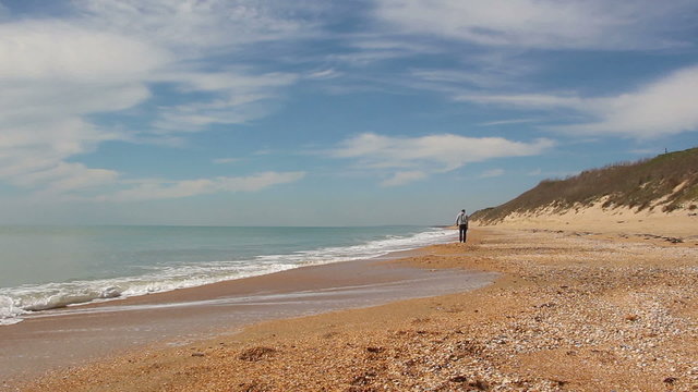 happy man goes along the beach in sunny summer day