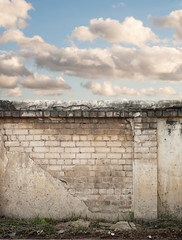 Blue sky with clouds behind the cracked wall background