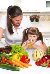 Beautiful young woman gives to the little girl orange juice  in