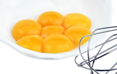 Egg yolks in a plate with a beater isolated on white background.