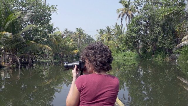 woman photographer exploring kerala backwaters by canoe