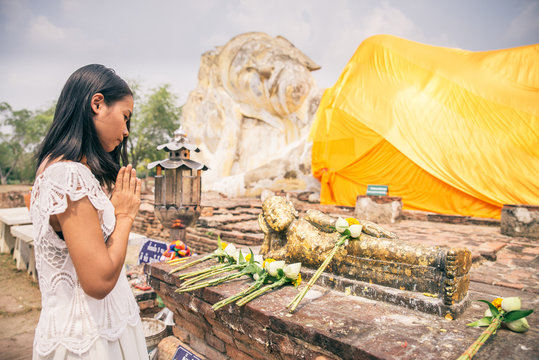 Woman praying at Buddha statue