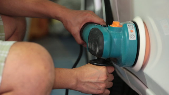 Worker Polishing the car with power buffer machine .