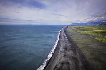 Fototapeta na wymiar The black sand beach with Icelandic coastline