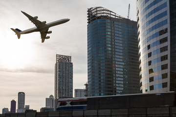 Fototapeta na wymiar airplane flying over city with sky train, Transportation concept