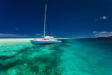 White catamaran in shallow tropical water with snorkeling reef - obrazy, fototapety, plakaty