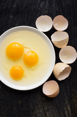 Three broken raw eggs on a white plate