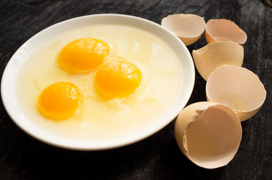 Three broken raw eggs on a white plate