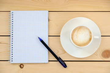 Empty blank with pen and cup of coffee on wooden table