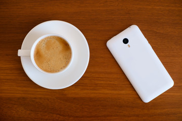 Smartphone with cup of espresso coffee on wooden table