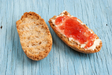 Rusk with butter and jam on old wooden table