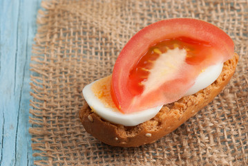 Rusk sandwich with egg and tomato on old wooden table