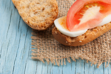 Rusk sandwich with egg and tomato on old wooden table