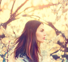 Beautiful model girl with long blowing hair in spring garden