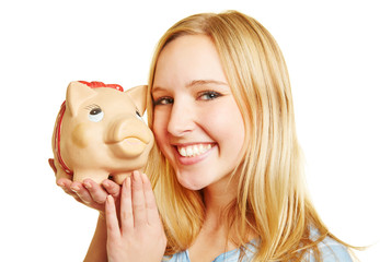 Frau lächelt mit Sparschwein auf der Hand
