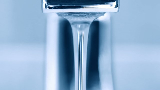 Open faucet in bathroom. Blue toned