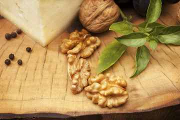 Organic walnuts and hard cheese on old wooden stump