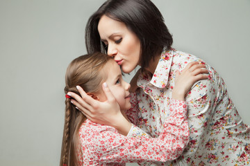 Beautiful and happy young mother kissing her small daughter.