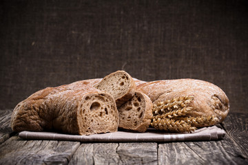 Tasty bread with wheat on wooden background.
