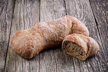 Tasty bread with wheat on wooden background.