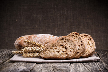 Tasty bread with wheat on wooden background.