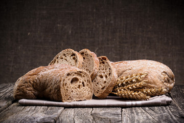 Tasty bread with wheat on wooden background.