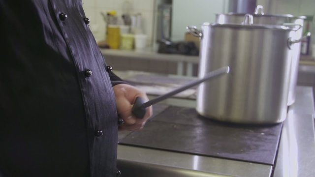 male chef sharpening knife in commercial kitchen