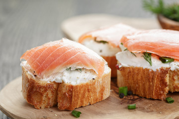 baguette slices with smoked salmon and cheese cream on wooden