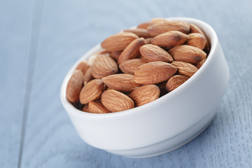 roasted almonds in white bowl on wooden table